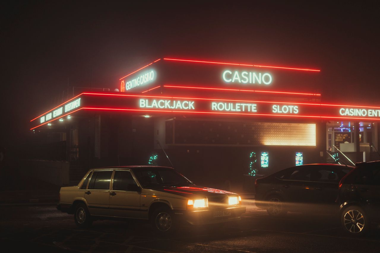 services-02 Vintage cars parked outside a neon-lit casino at night, showcasing urban nightlife.