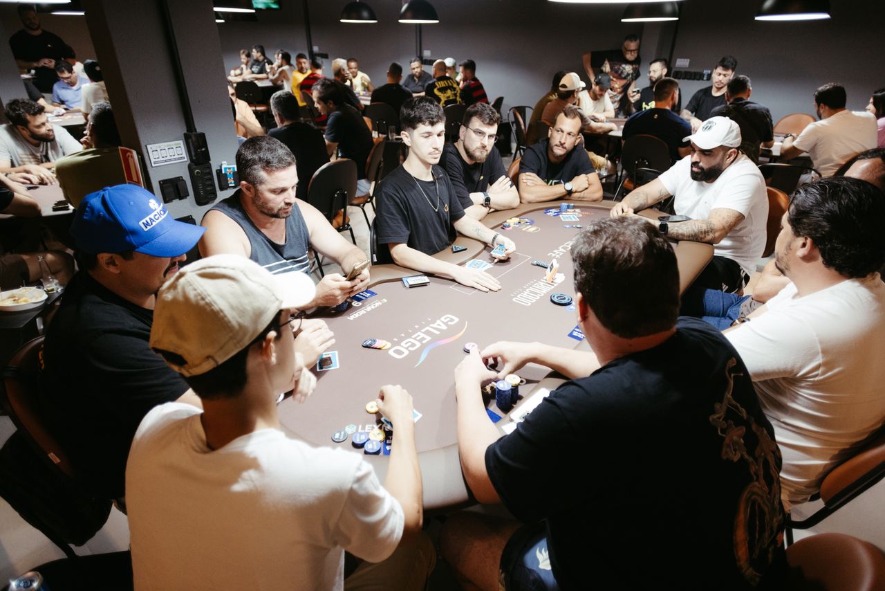 A group of adult men engage in a lively poker game at a vibrant casino setting.