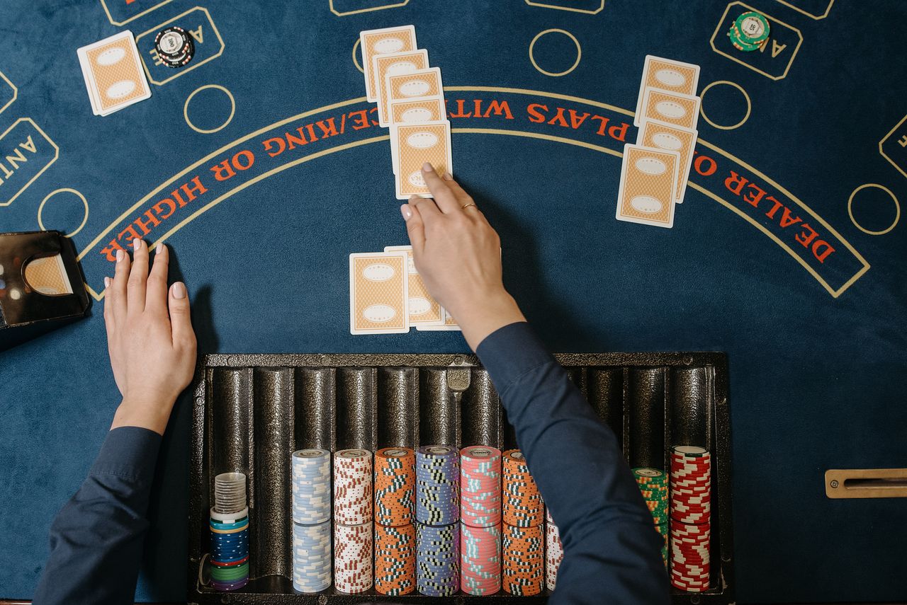 services-02 Dealer hands distributing cards at a casino blackjack table with chips in view.